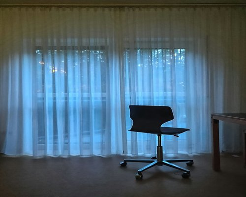 A warm lit room with natural light coming through sheer curtains onto a desk