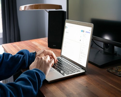 A person typing on a laptop computer under balanced workspace illumination